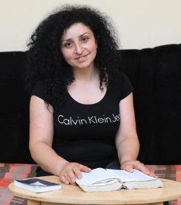 Satik sitting on a couch with a book on a table