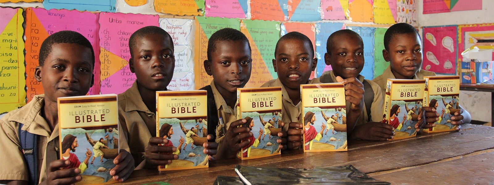 Children sitting at a table holding books