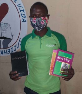 Damião standing with the Bible in one hand and a book on the other